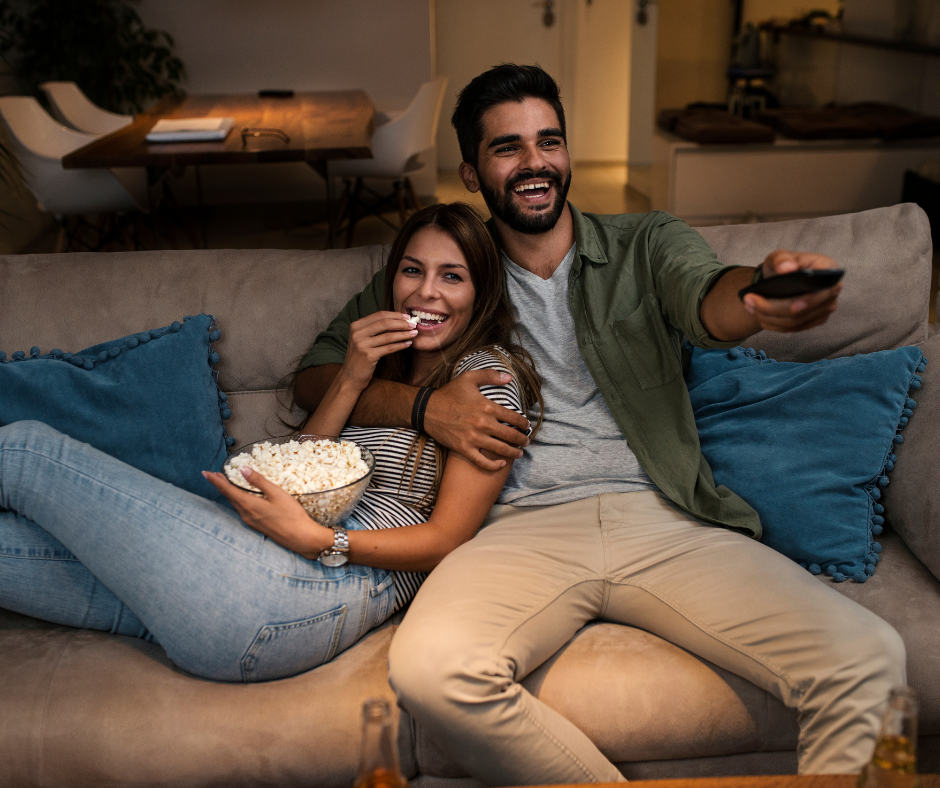 Military Couple watching tv together on the couch eating popcorn