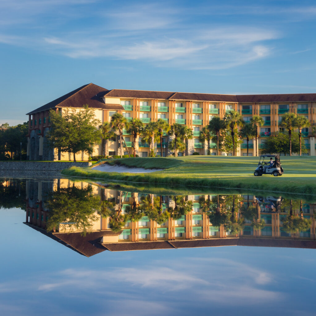 Exterior of Shades of Green Military Disney World Resort with a golf cart passing by a beautiful pond
